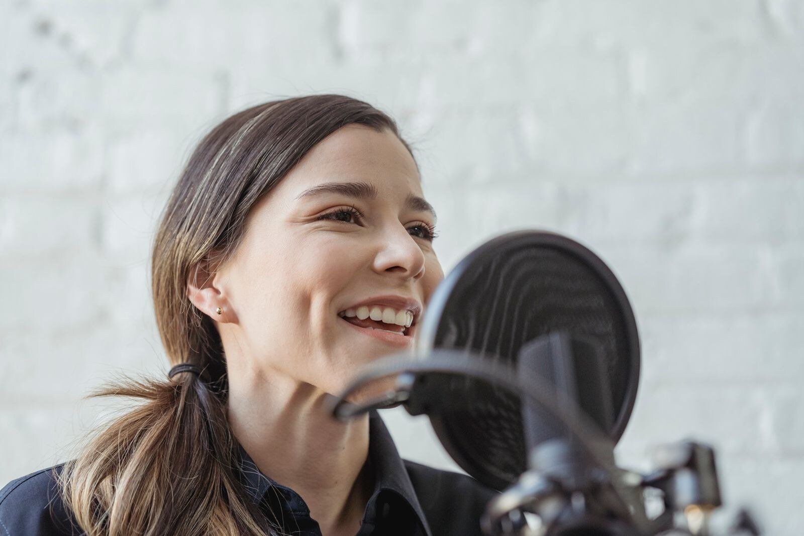 A woman recording her voice with a studio microphone